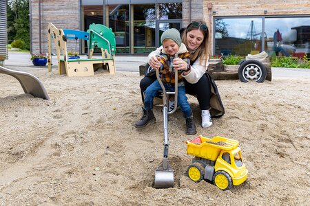 Junge spielt mit Mutter im Sandkasten