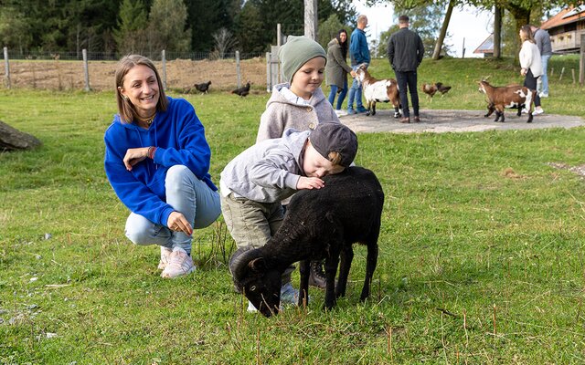 Jungs streicheln eine schwarze Ziege